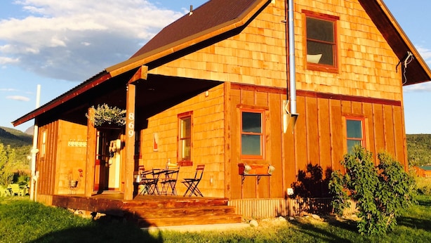 A wooden cabin with a porch, a chimney, and a number '860' on the side. - Sweet and charming Victor home on three acres with Teton views! (Victor)
