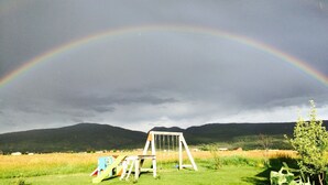 A grassy field with a swing set and a rainbow in the sky. - Sweet and charming Victor home on three acres with Teton views! (Victor)