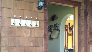 A wooden interior with a wall-mounted light fixture, a door leading to another room, and a metal plant stand with flowers. - Sweet and charming Victor home on three acres with Teton views! (Victor)