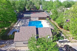 A residential property with a swimming pool, tennis courts, and a covered patio area.