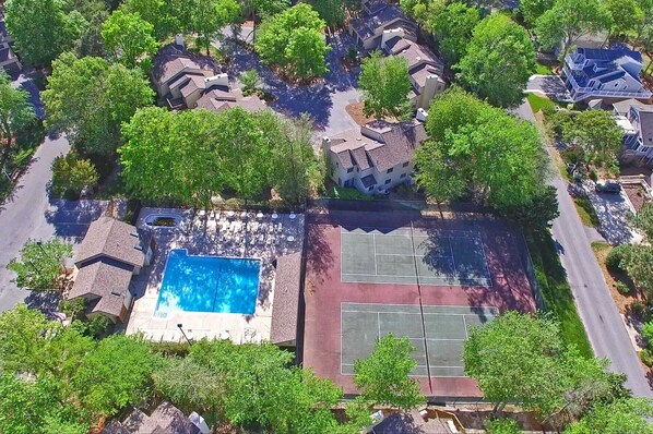 An aerial view of a residential area with a swimming pool and tennis courts.