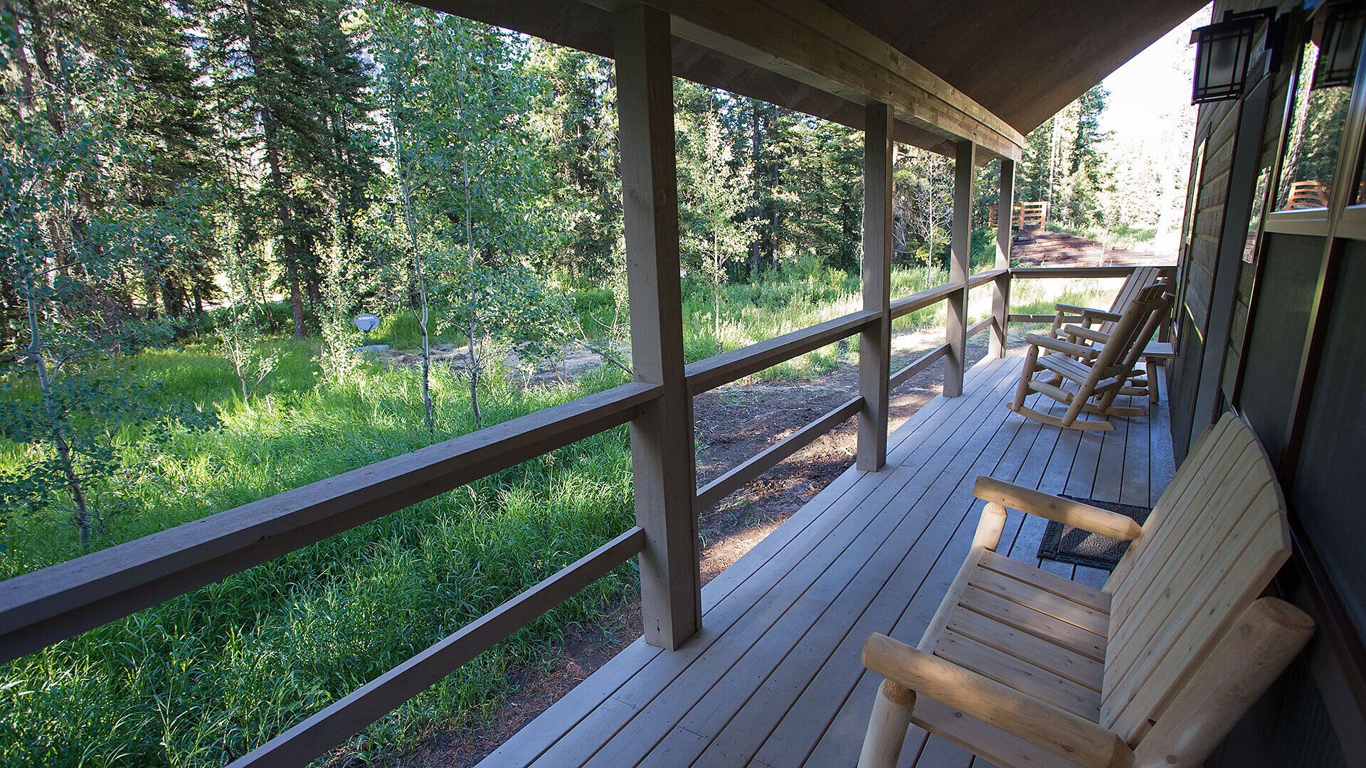 Relax on the porch, which faces the trees and Soda Butte Creek.