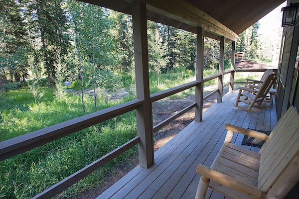 Relax on the porch, which faces the trees and Soda Butte Creek.