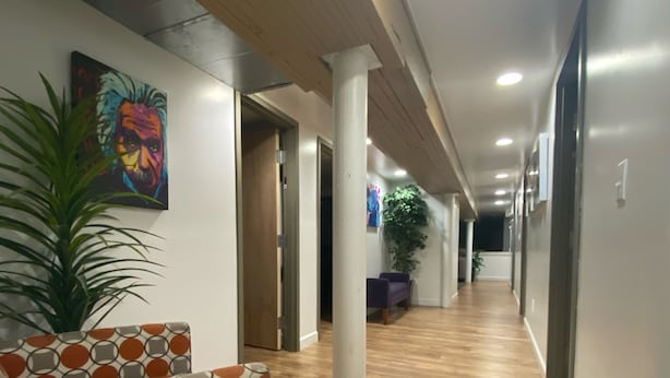 Ein Flur mit Holzboden, einem gemusterten Sofa und einem Bild an der Wand.