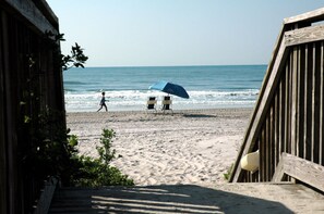 A beach with a wooden boardwalk, a blue umbrella, and two beach chairs. - Beautiful Tropical Decor. Private Access. Close to Ocean Beach and Pools.  (Myrtle Beach)