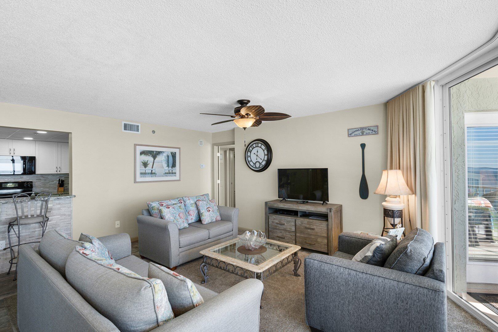 A living room with a grey sofa, a coffee table, a television, and a ceiling fan.