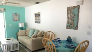 A dining area with a teal tablecloth, wooden chairs, and a beige sofa. - STEPS TO BEACH & STEPS TO BAY & TO WATCH DOLPHINS! 3 MIN WALK TO RESTAURANTS (Englewood)