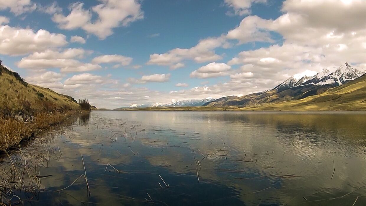 A calm lake with mountains in the background.