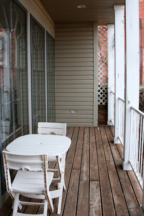 A wooden deck with a white table and chairs, a glass door, and a white fence. - Apt. G above G Gallery & Glass Studio in a beautiful 1890 historic building (Guthrie)