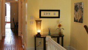 Ein Flur mit Holzdielen, einer weißen Geländer, einem Tisch mit Lampe und einem gerahmten Schild an der Wand.