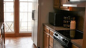 Eine Küche mit Holzausstattung, einem Kühlschrank, einer Mikrowelle und einem Backofen.