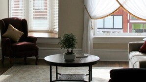 Ein Wohnzimmer mit rundem Couchtisch, einem roten Sessel, einem weißen Sessel und einem Blumentopf.