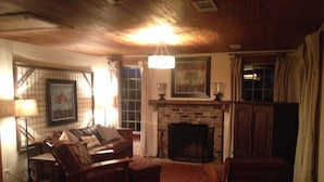 Una sala de estar acogedora con chimenea, muebles de madera y un cuadro enmarcado en la pared.