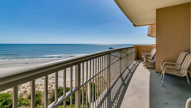 A balcony with a view of the beach and ocean.