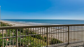 A balcony with a view of a beach and ocean.