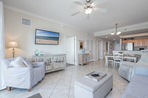 A spacious living room with a ceiling fan, a dining area, and a kitchen with wooden cabinets.