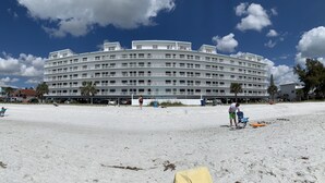 Een groot, meerlaags hotel met balkons en een strand ervoor.