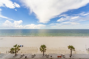Una playa con una terraza de madera, palmeras y una vista despejada del océano.