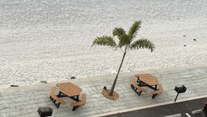 Een promenade aan het strand met picknicktafels en een palmboom.