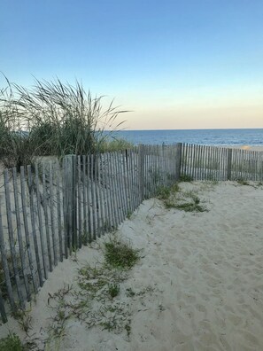 A sandy beach with a wooden fence and sparse vegetation. - Beautiful updated condo w modern decor, overlooking Fenwick lighthouse from deck (Ocean City)