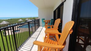A balcony with a pool, outdoor seating, and a view of the ocean. - Seas Life's Moments - Condo 202: Spacious 2BR retreat in South Padre Island, sleeps 7. (South Padre Island)