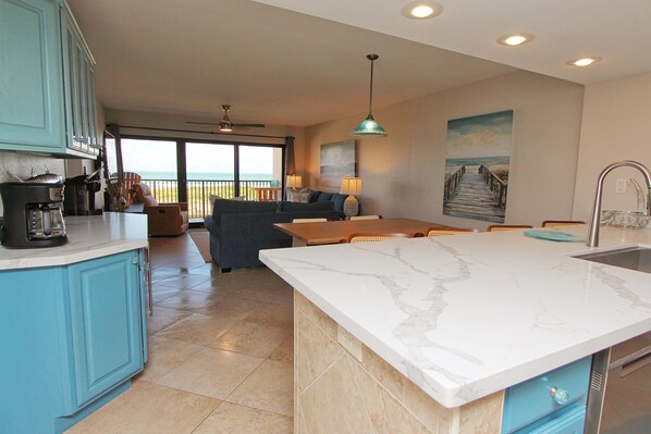 A modern kitchen with a large island, a dining area with a view, and a balcony.