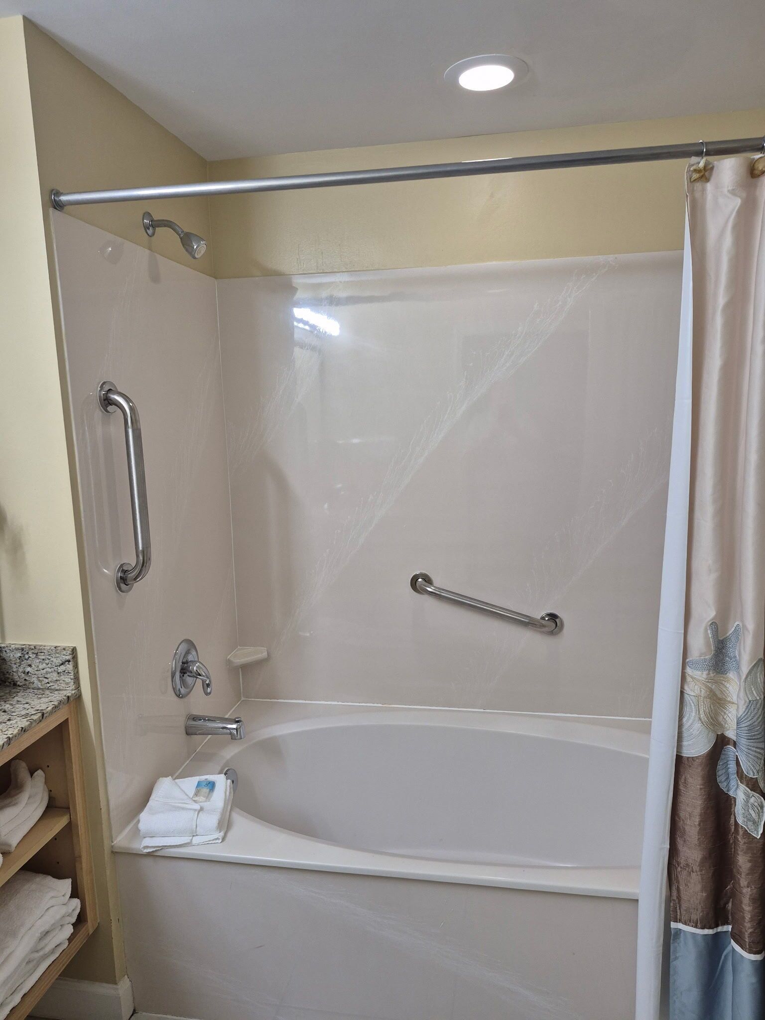Ein Duschbereich mit Badewanne, Haltegriffen und Handtuchhalter.