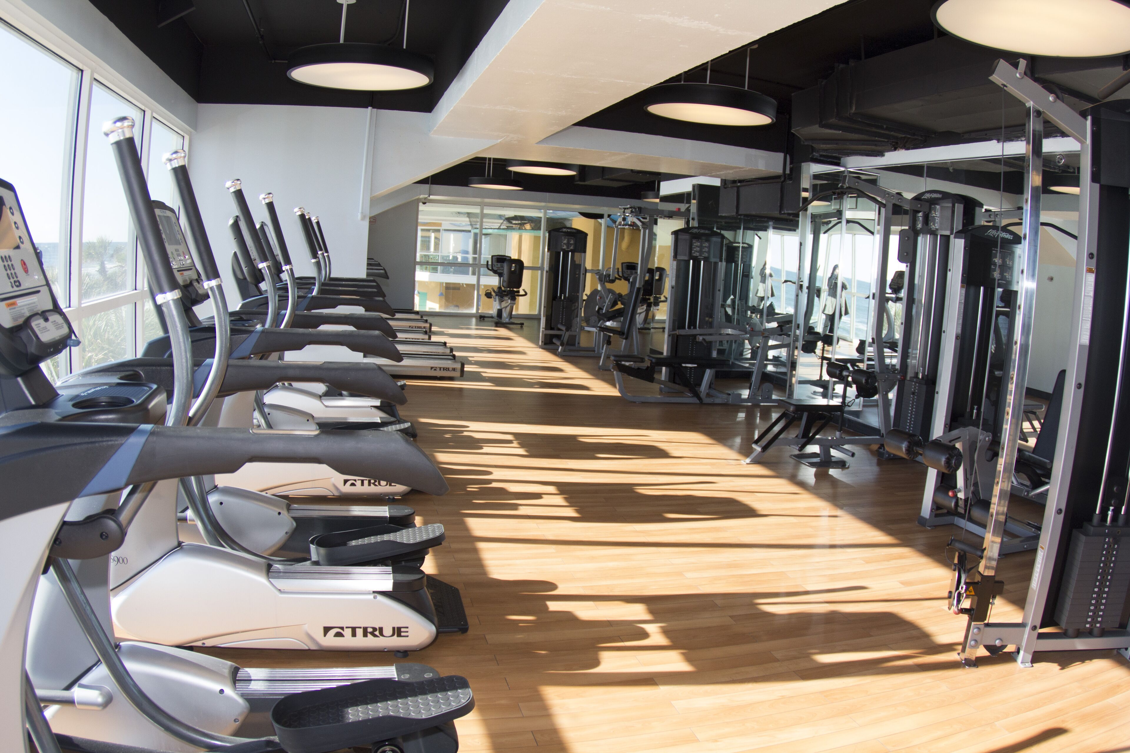 Une salle de sport équipée de tapis de course, d’appareils de musculation et de miroirs.