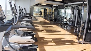 Un gimnasio con cintas de correr, máquinas de pesas y equipamiento de ejercicio.