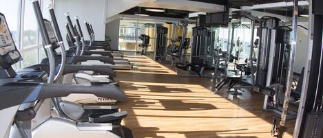 Une salle de sport équipée de tapis de course, d’appareils de musculation et de miroirs.