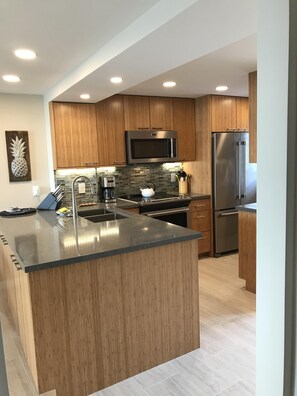 A modern kitchen with wooden cabinets, stainless steel appliances, and a large island.