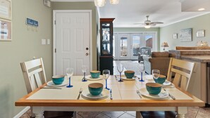 A dining area with a table set for four, chairs, and a view into the living room.