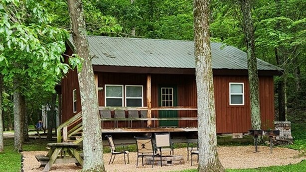 A rustic cabin with a porch, surrounded by trees. - Getaway Cabin next door to Maramec Spring Park & Meramec River Trophy Trout (St James)