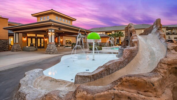 A hotel with a large entrance, outdoor water features, and a distinctive rock formation.