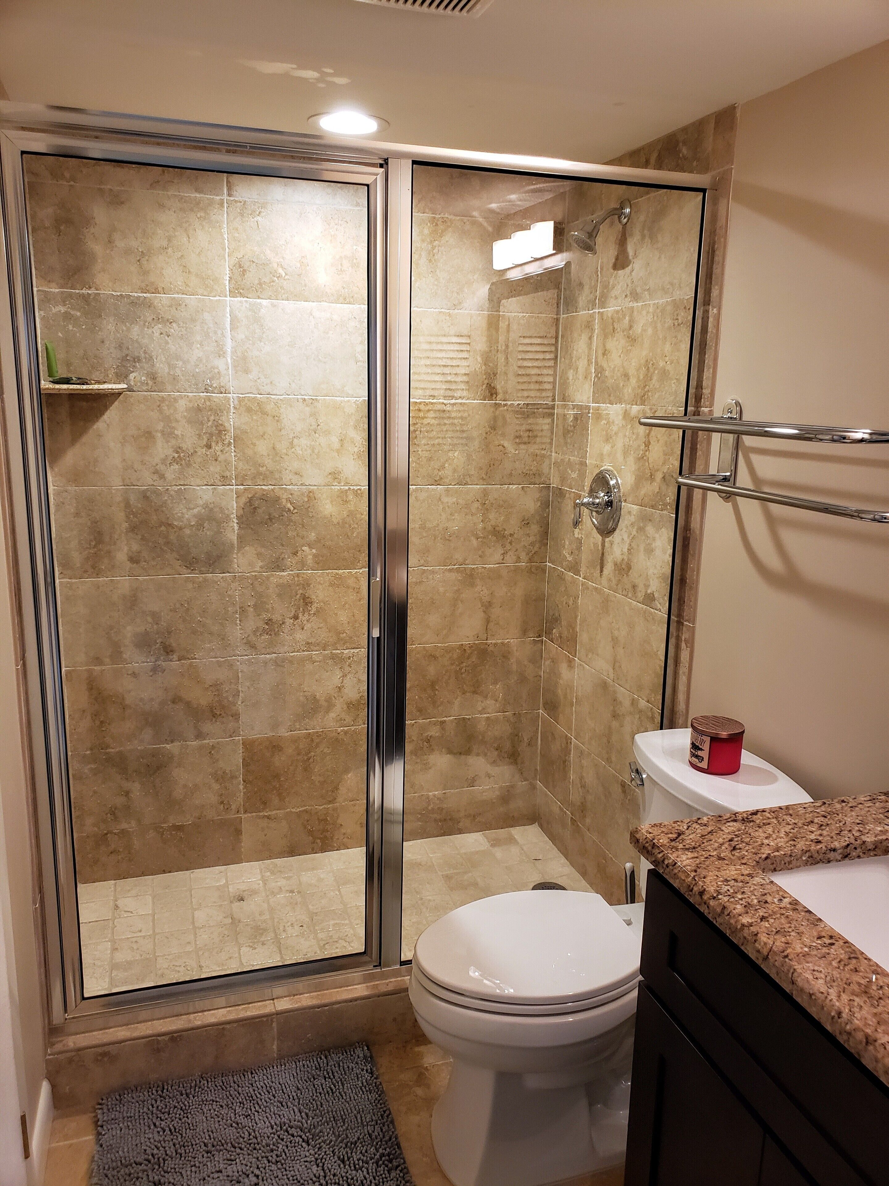 Une salle de bain dotée d’une douche à parois de verre, de toilettes et d’un lavabo avec un plan de travail en granit.