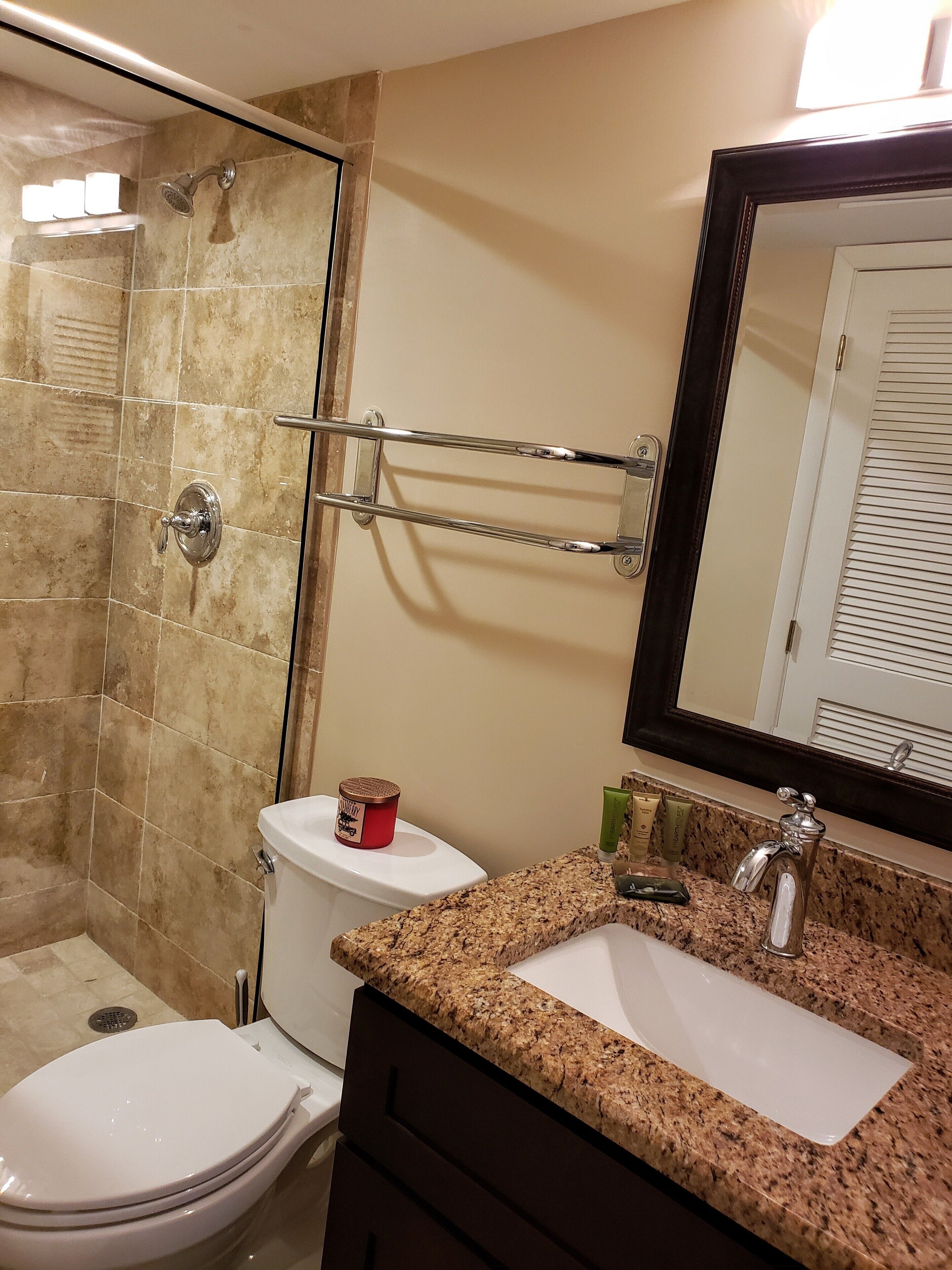 Un baño con ducha, inodoro, lavabo y espejo.