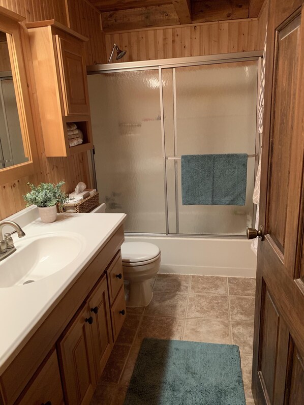 A wooden bathroom with a sink, toilet, and shower.