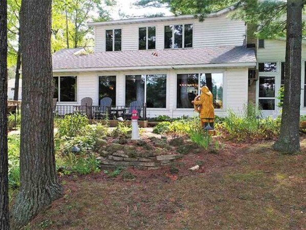A two-story house with a covered porch and a stone water feature. - Sandy Bottom Lodge on the Beautiful Chain O Lakes in Waupaca (Waupaca)