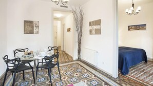 Un espace repas avec une table dressée pour quatre personnes, un lustre et un revêtement de sol à motifs.