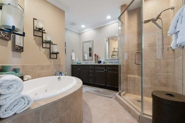 Un baño moderno con una bañera independiente, muebles oscuros, una cabina de ducha de vidrio y un espejo grande.