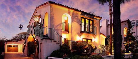 A two-story house with a balcony, a staircase, and a driveway leading to a garage.