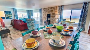 A dining area with a wooden table set for a meal, surrounded by colorful chairs and bowls.