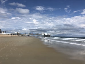 Une plage avec une jetée qui s’avance dans l’eau, et sur laquelle se trouve un bâtiment portant une enseigne.