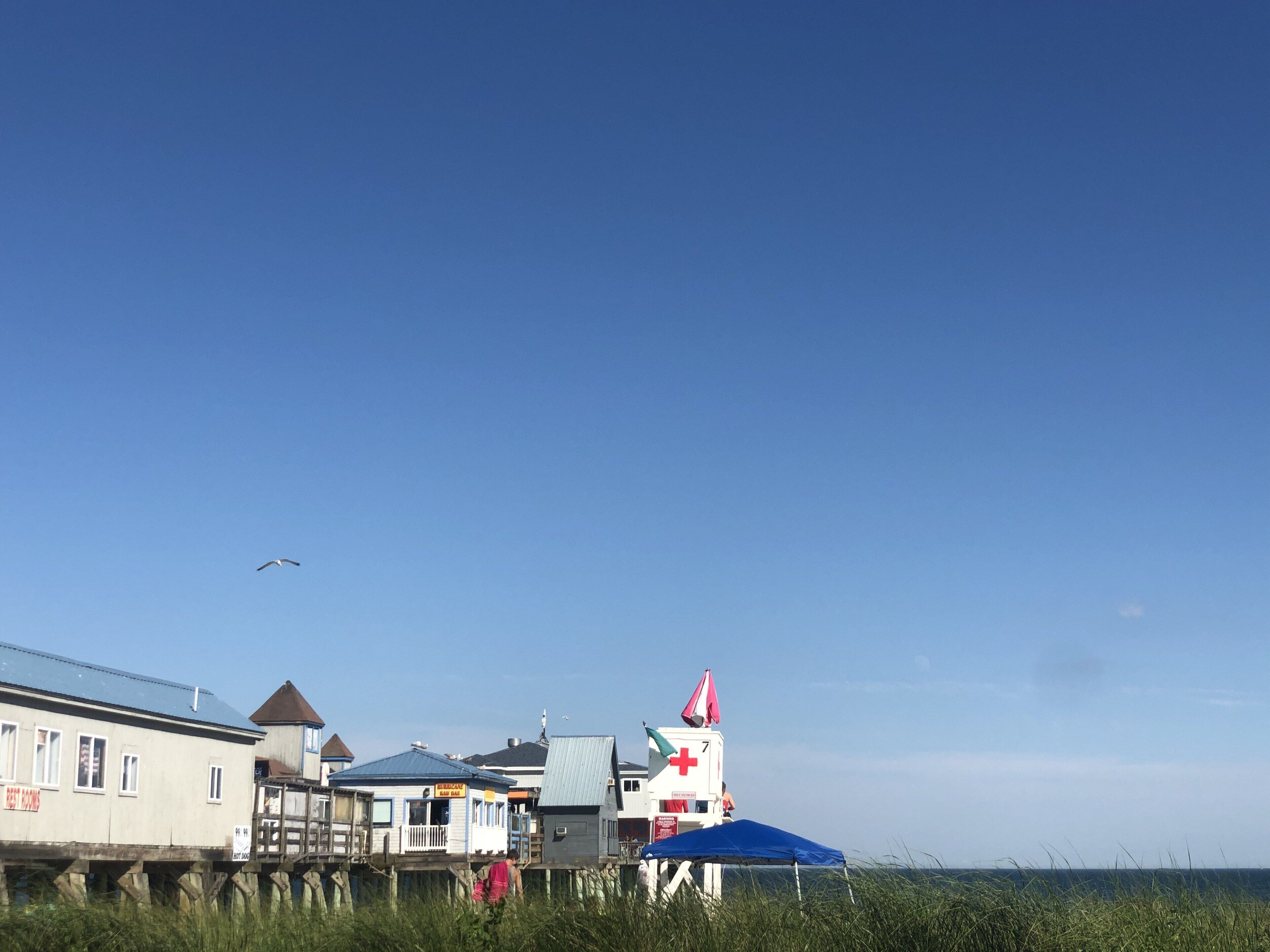 Un edificio sul lungomare con una torretta per i bagnini, un cartello con scritto 'Best Rooms' e una tenda blu.