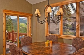 Enjoy meals in this dining area with a round table and comfortable chairs, surrounded by large windows offering a view of the mountains.