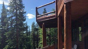 A hot tub with a wooden deck and railing, surrounded by tall trees and a clear sky. - Luxury Home, Family Friendly, 4900 Sq Foot, 6 BR Ski in/Out! (Breckenridge)