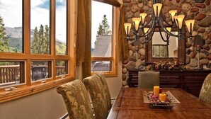 A dining area with a stone wall, a chandelier, and a table with candles. - Luxury Home, Family Friendly, 4900 Sq Foot, 6 BR Ski in/Out! (Breckenridge)