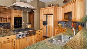 A modern kitchen with wooden cabinets, a stainless steel range hood, granite countertops, and a built-in sink. - Luxury Home, Family Friendly, 4900 Sq Foot, 6 BR Ski in/Out! (Breckenridge)