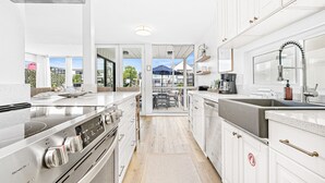A modern kitchen with stainless steel appliances, white cabinetry, and a view to the outside.