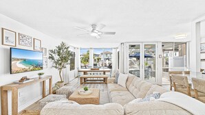 A spacious living room with a large sectional sofa, a wooden coffee table, and a ceiling fan.